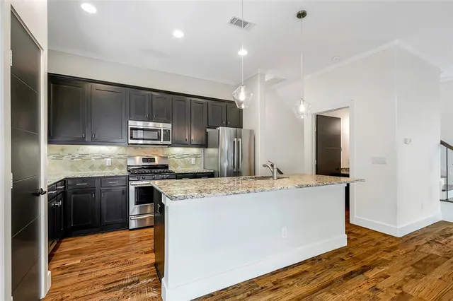 a large kitchen with granite countertop a stove top oven a sink dishwasher a refrigerator and cabinets with wooden floor