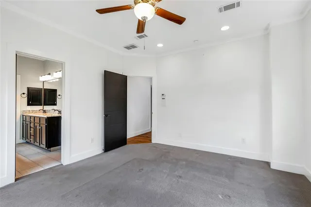 an empty room with a kitchen and a ceiling fan