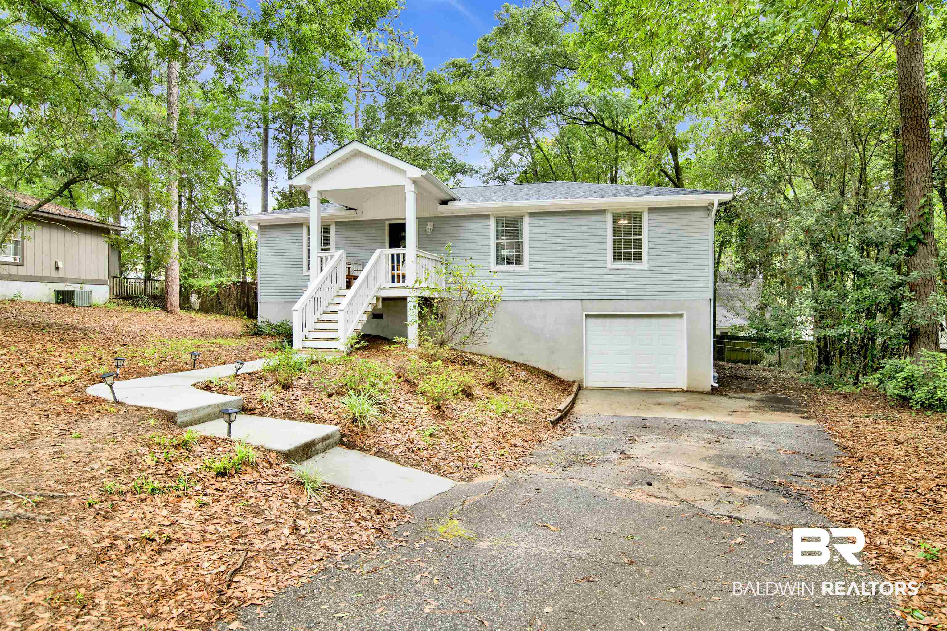 253 Maplewood Loop Daphne, AL 36526 - Photo 30 of 30 Light blue siding exterior featuring a covered front porch with white railings, an attached garage, and a concrete walkway with integrated lighting
