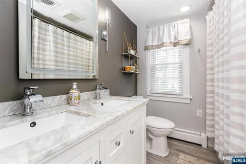 a bathroom with a granite countertop sink a toilet and a mirror