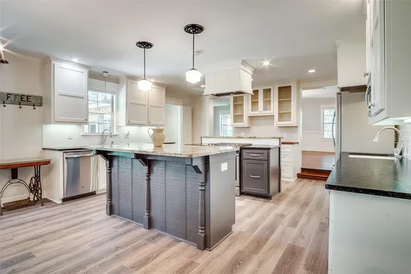 a kitchen with stainless steel appliances granite countertop a sink a stove and a wooden floors