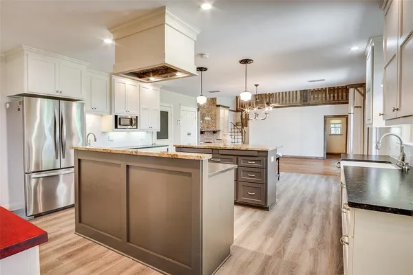 a kitchen with stainless steel appliances granite countertop a refrigerator a stove and a sink