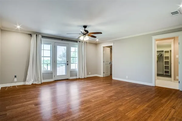 a view of an empty room with window and wooden floor