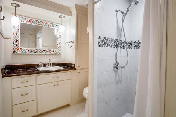 a bathroom with a granite countertop sink a mirror and a shower