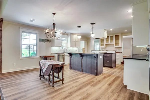 a kitchen with stainless steel appliances granite countertop wooden floors and white cabinets