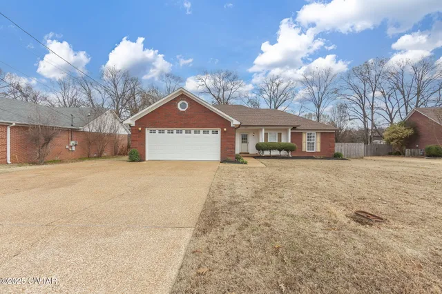 a front view of a house with a yard and trees