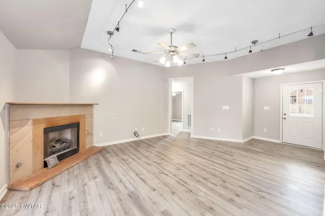 an empty room with wooden floor fireplace and window