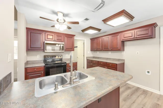 a kitchen with stainless steel appliances granite countertop a sink dishwasher stove and refrigerator with wooden floor