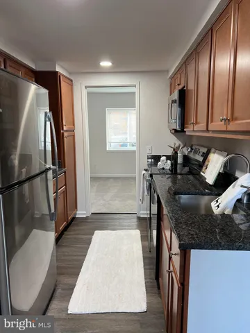 a kitchen with granite countertop a refrigerator stove and sink