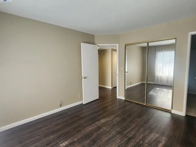 an empty room with wooden floor & closet area