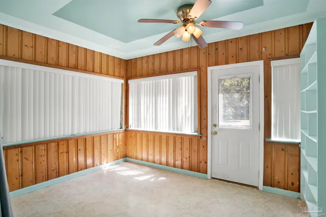 a view of an empty room with chandelier fan