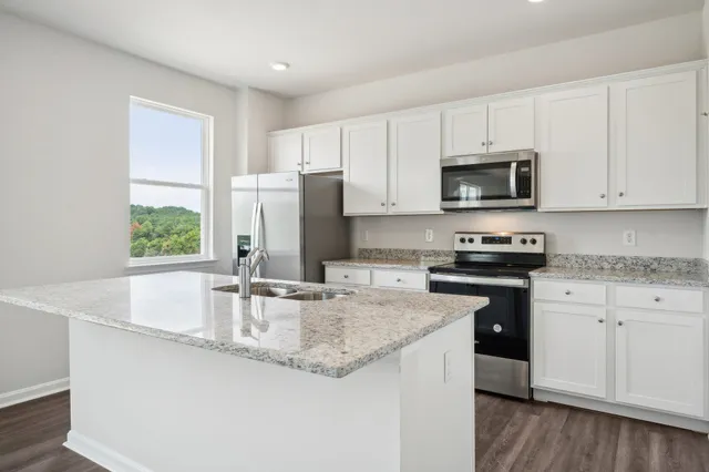 a kitchen with granite countertop a sink stainless steel appliances and white cabinets