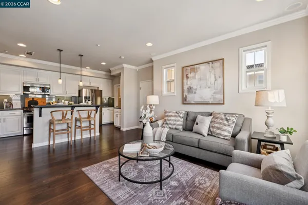 a living room with furniture kitchen view and a wooden floor