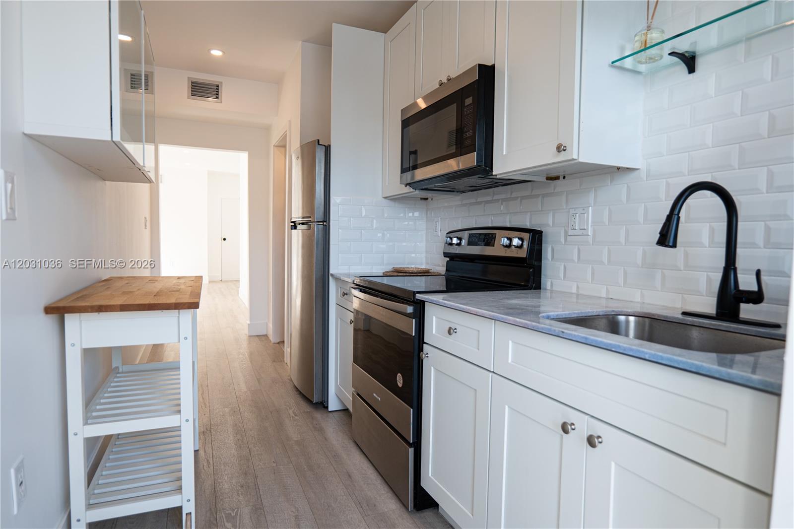 1721 Southwest 13th Street, Unit 4 Miami, FL 33145 - Photo 4 of 24 a kitchen with stainless steel appliances granite countertop a stove a microwave and a refrigerator
