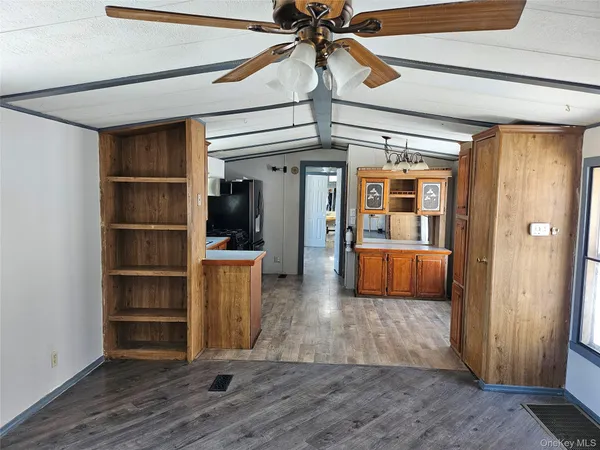 a view of a hallway to room with wooden floor and cabinet