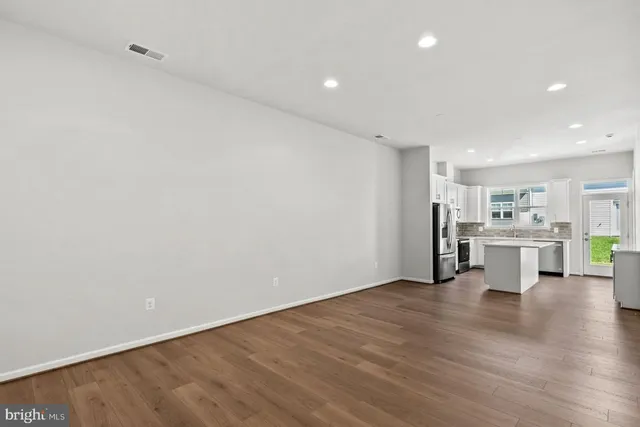 a view of a kitchen with chairs and wooden floor
