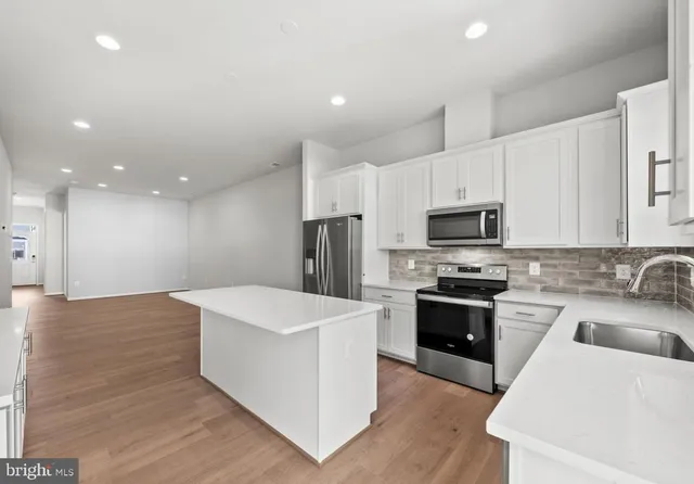 a kitchen with stainless steel appliances kitchen island sink refrigerator and cabinets