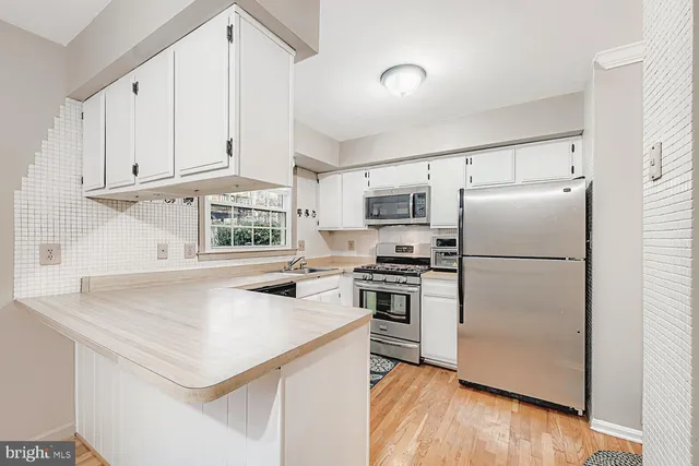 a kitchen with stainless steel appliances a refrigerator a stove a sink and a window