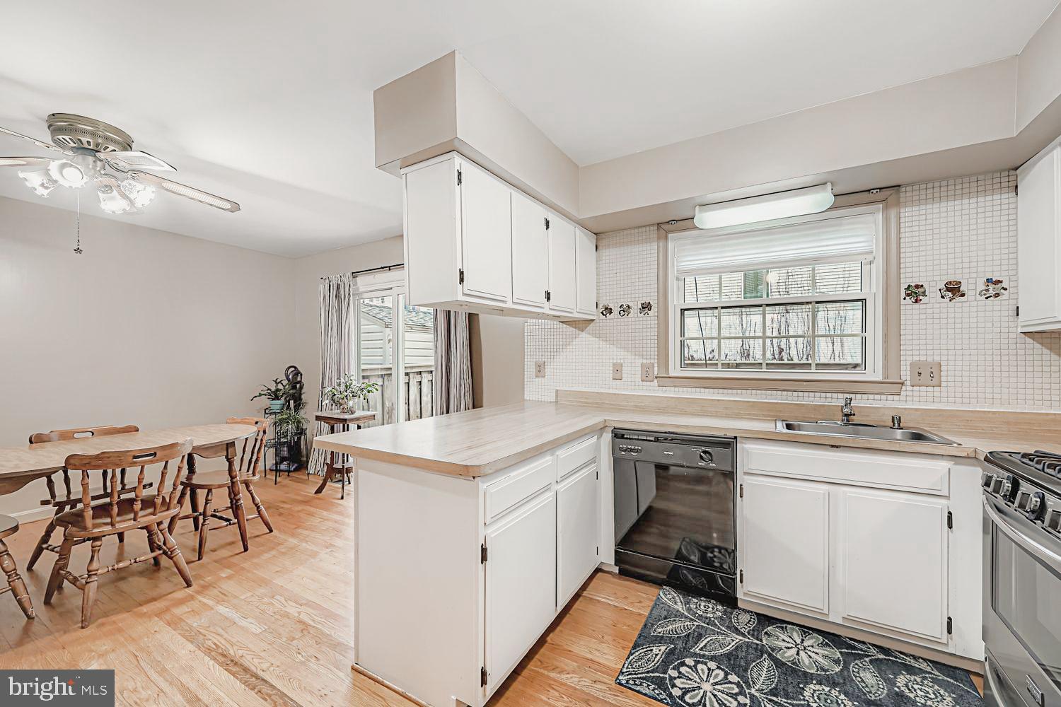 13229 Country Ridge Drive Germantown, MD 20874 - Photo 10 of 24 a kitchen with a stove a sink and white cabinets with wooden floor