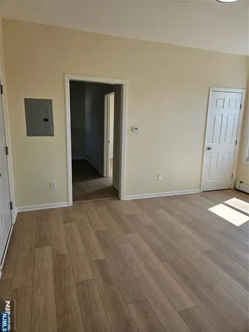 a view of an empty room with wooden floor and closet