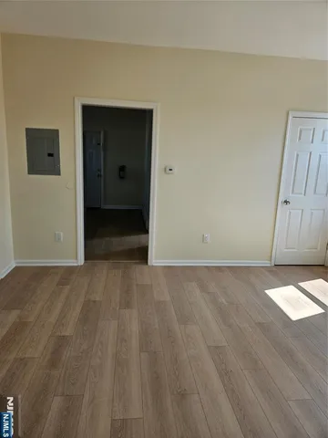 a view of an empty room with wooden floor and cabinet