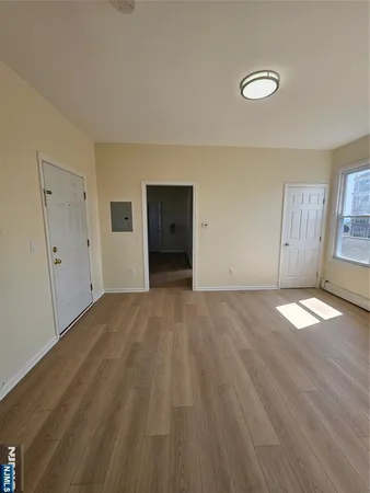 a view of empty room with wooden floor and window