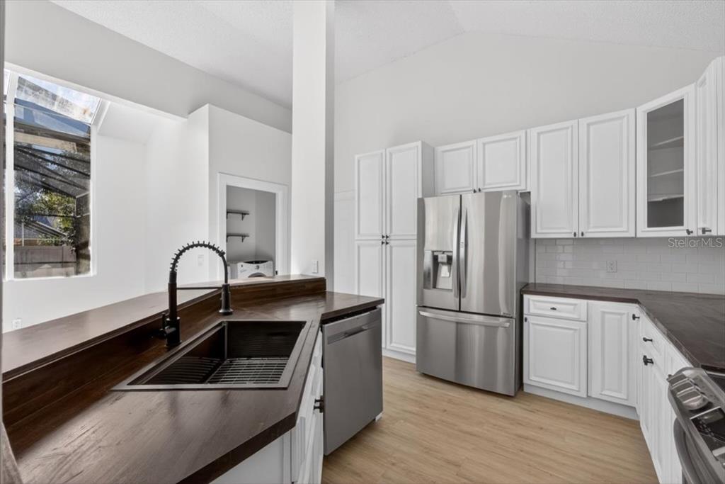 8618 Valley Ridge Court Orlando, FL 32818 - Photo 10 of 24 a kitchen with a refrigerator sink and white cabinets