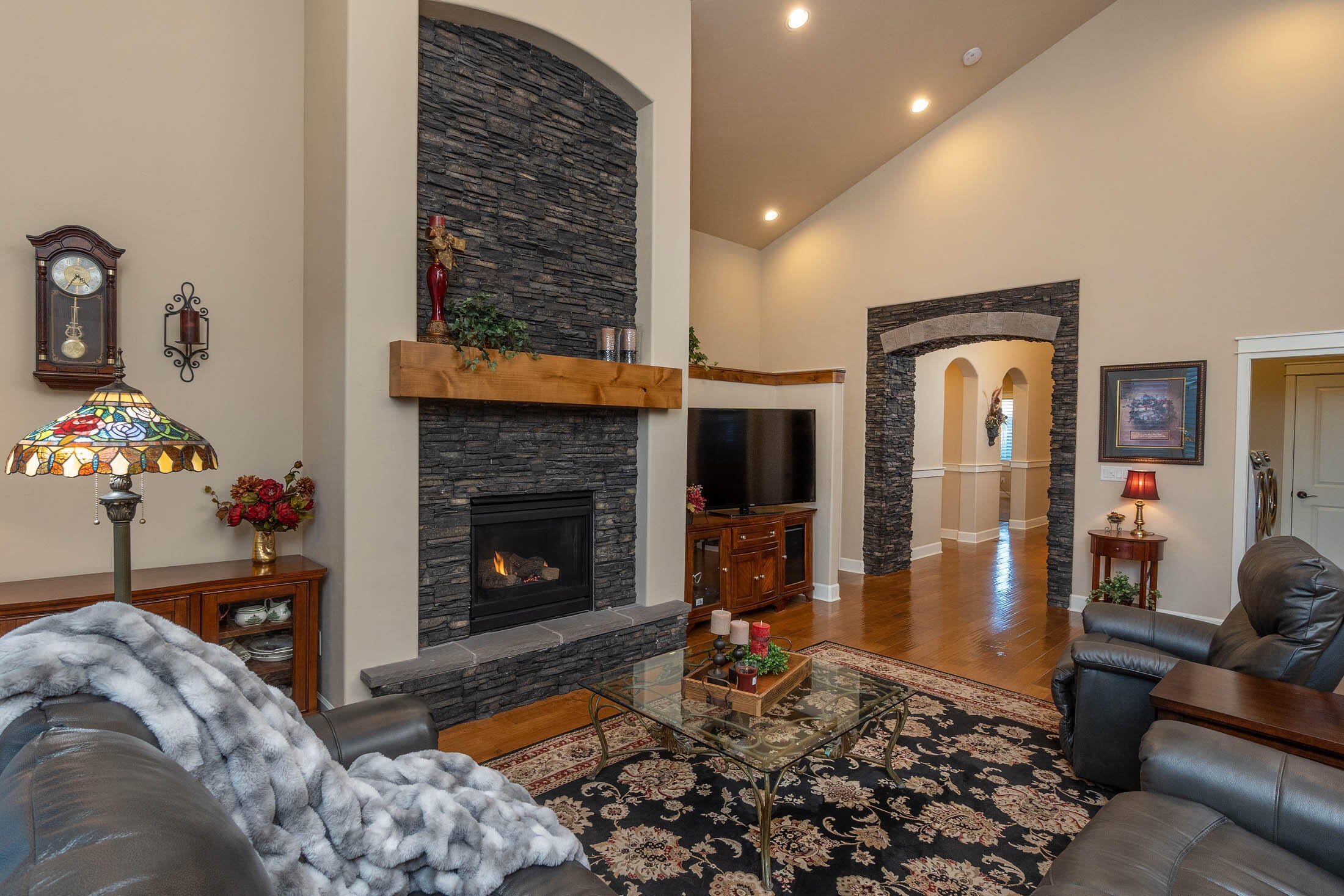 61129 Manhae Loop Bend, OR 97702 - Photo 5 of 44 Greatroom gas fireplace with upgraded stone extending above stained mantle. Upgraded stained crown on tall pony wall hall leading to primary suite (middle of photo)
