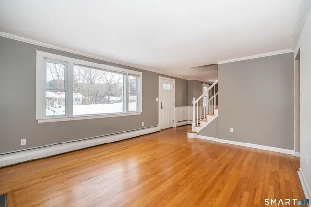 a view of an empty room with wooden floor and a window