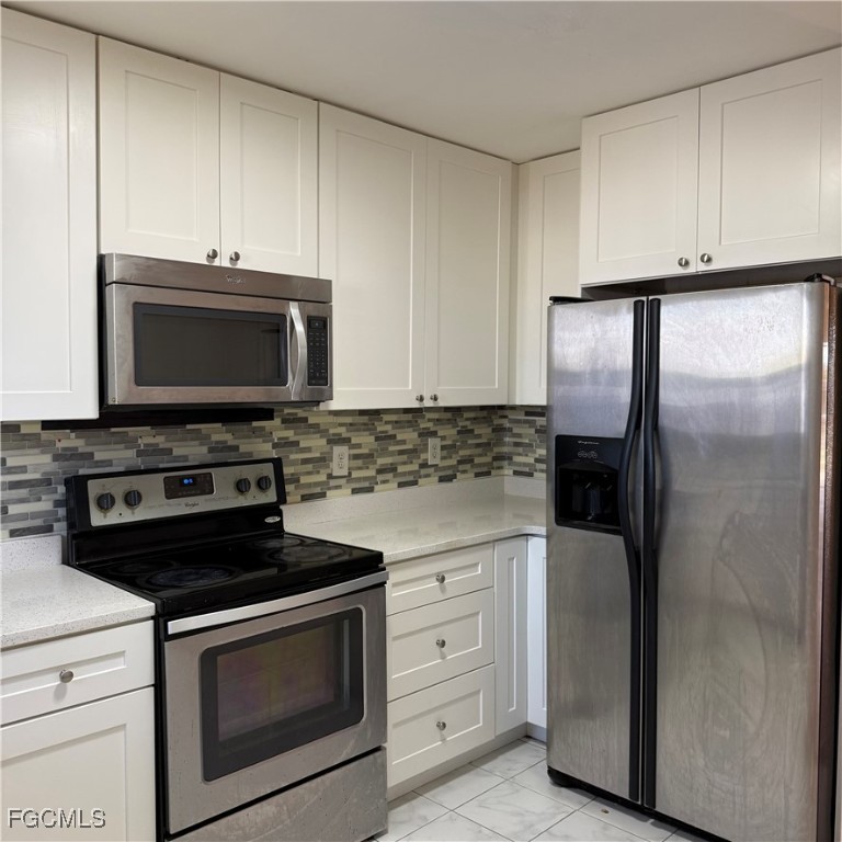2172 Simon Court Fort Myers, FL 33916 - Photo 9 of 15 a kitchen with stainless steel appliances white cabinets and a stove a refrigerator with wooden floors