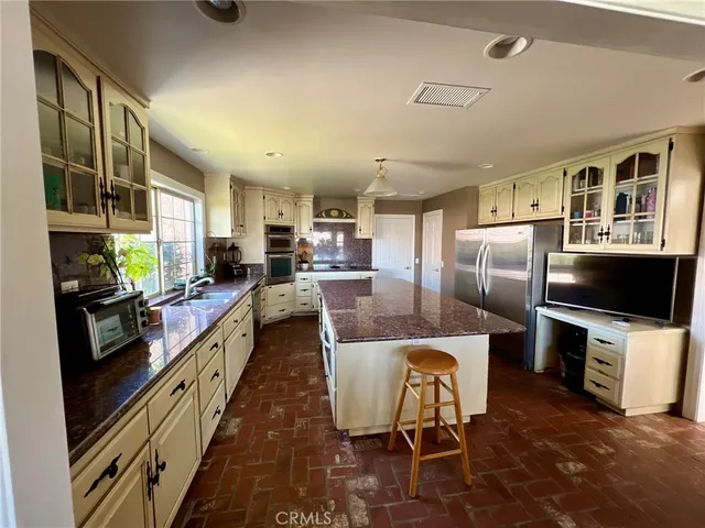 a kitchen with stainless steel appliances granite countertop a stove a refrigerator a oven a sink with a dining table and chairs with wooden floor