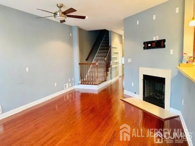 a view of an empty room with wooden floor fireplace and a window