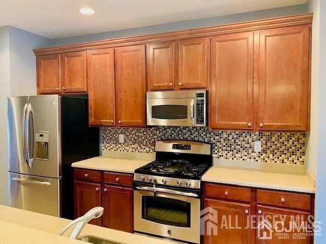a kitchen with granite countertop a stove a sink and a refrigerator