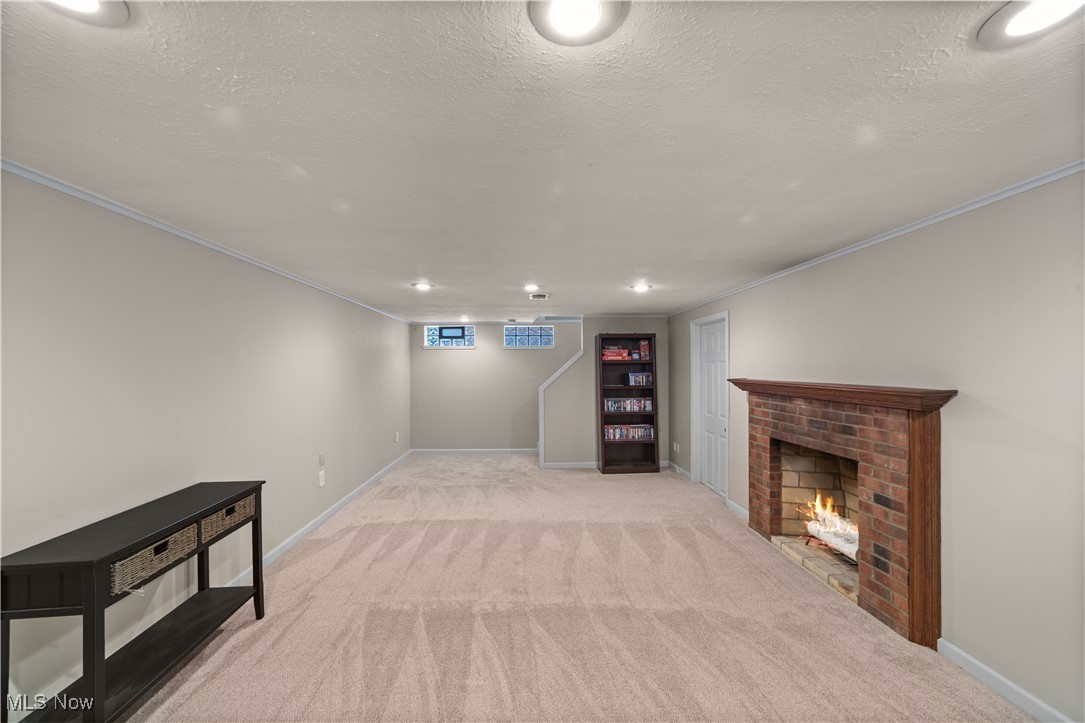 3826 Faversham Road Cleveland, OH 44118 - Photo 26 of 40 Below grade area with carpet, ornamental molding, baseboards, a fireplace, and a textured ceiling