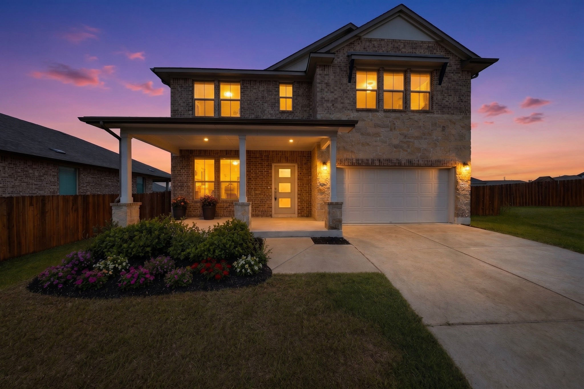 16809 Guido Cove Pflugerville, TX 78660 - Photo 2 of 40 Two-story residence featuring a brick and stone facade, covered front porch with columns, a two-car garage, and landscaped front beds