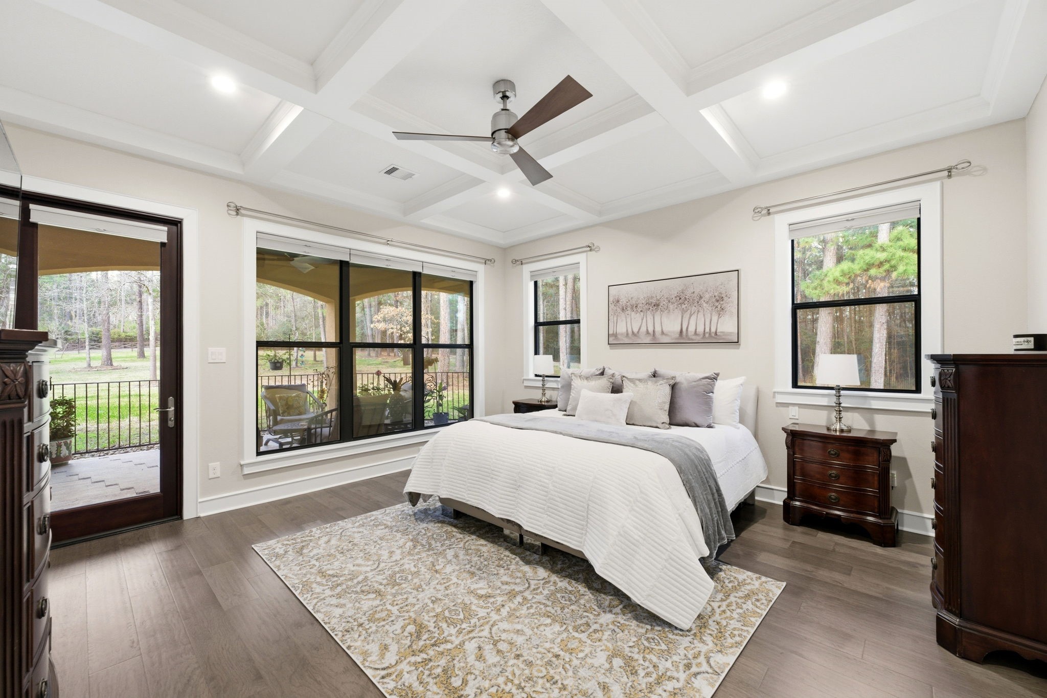 280 Sundog Road Huntsville, TX 77340 - Photo 22 of 50 Spacious primary bedroom featuring hickory wood flooring, coffered ceiling, abundant windows, and a glass door providing direct access to the front loggia.