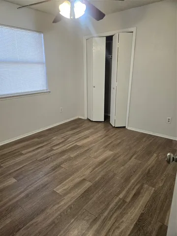 a view of an empty room with wooden floor and a chandelier fan