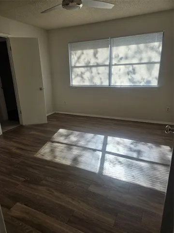 a view of empty room with wooden floor and fan