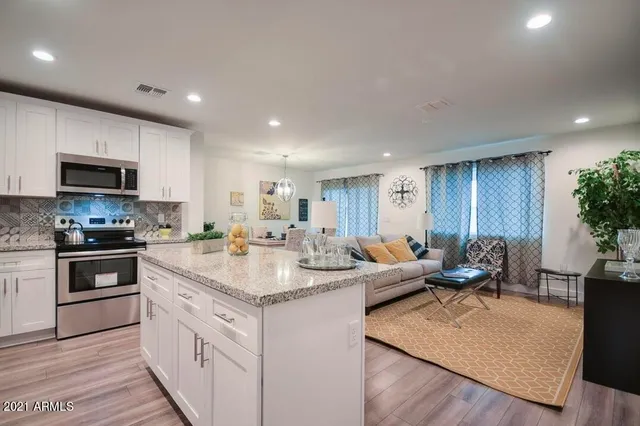 a kitchen with stainless steel appliances granite countertop a stove top oven a sink dishwasher and a refrigerator with wooden floor