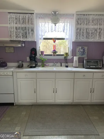 a kitchen with white cabinets and window