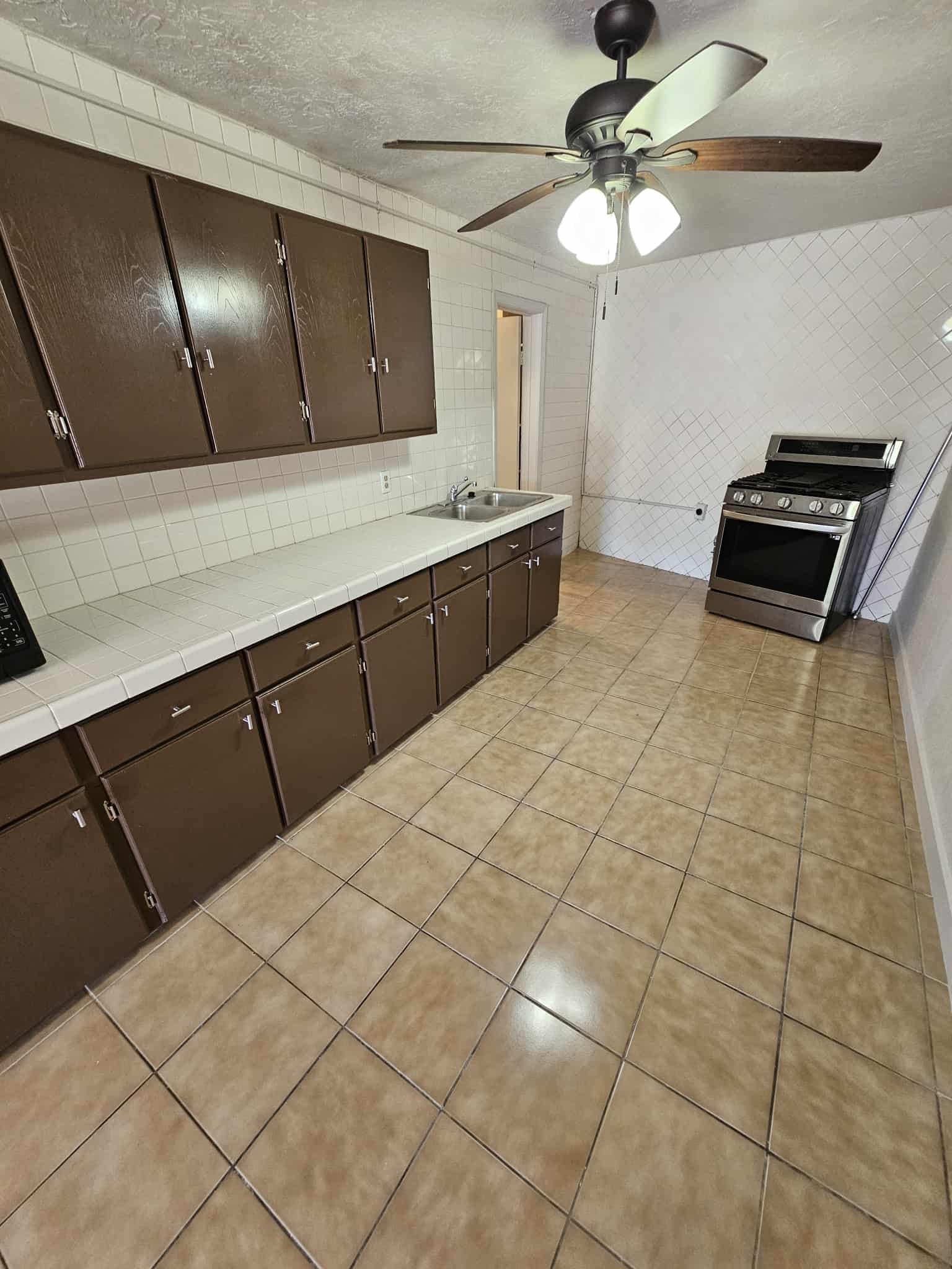 4115 Bering Street, Unit B Houston, TX 77003 - Photo 5 of 8 a kitchen with stainless steel appliances a sink a stove cabinets and living room view