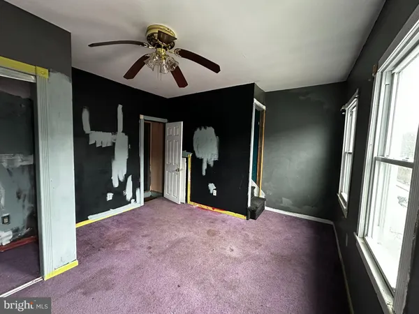 an empty room with windows and fan