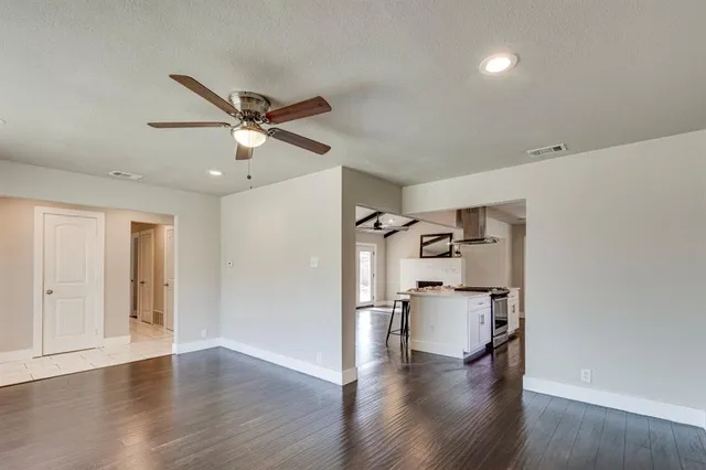a view of a big room with wooden floor a ceiling fan and windows