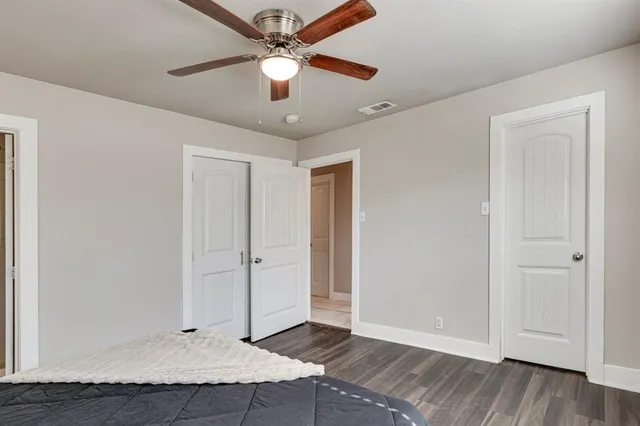 an empty room with wooden floor and ceiling fan