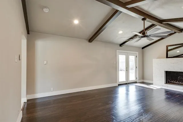 an empty room with wooden floor fireplace and windows
