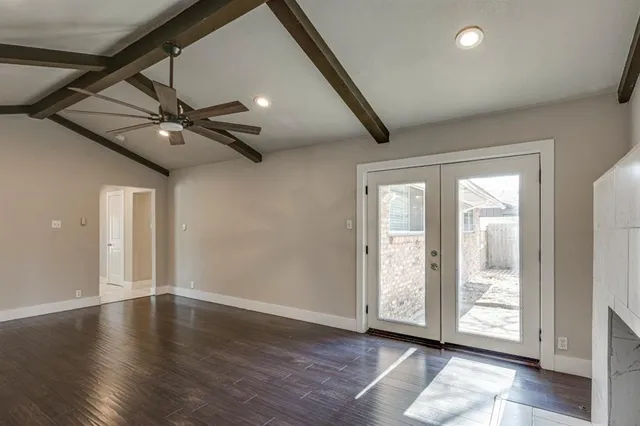 a view of an empty room with a window and wooden floor