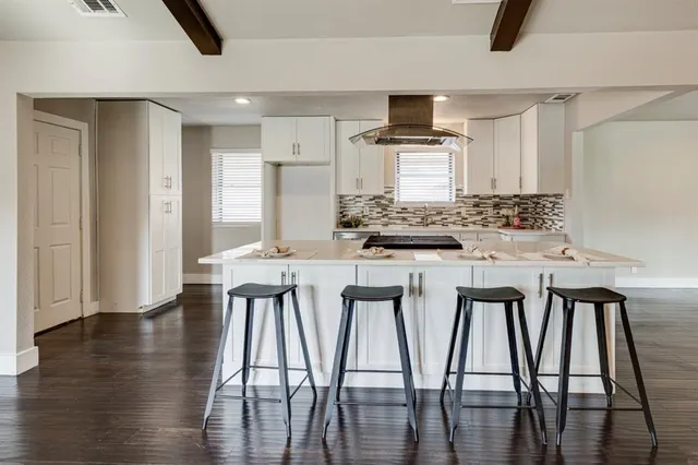 a dining room with stainless steel appliances kitchen island granite countertop a dining table chairs and a refrigerator