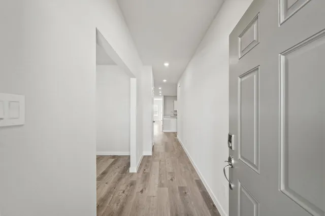 a view of a hallway with wooden floor and a bathroom