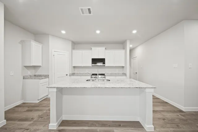 a kitchen with stainless steel appliances granite countertop a sink a stove a refrigerator and white cabinets
