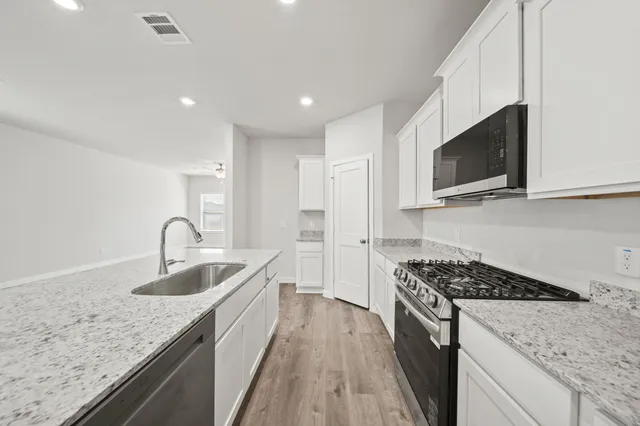 a kitchen with stainless steel appliances granite countertop a sink stove and microwave